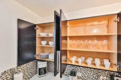a kitchen with wooden cabinets and glasses on shelves at Release your nature in Hallandale Beach