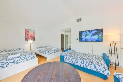 a room with three beds and a table at Haunted corner of Aventura Villa in Miami