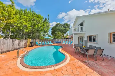a swimming pool with chairs and a table next to a house at Haunted corner of Aventura Villa in Miami