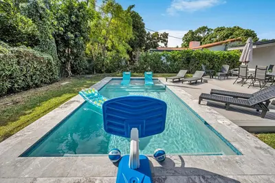 a pool with a blue chair in a backyard at The Design District Pool House in Miami