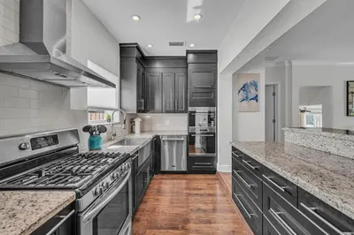 a large kitchen with stainless steel appliances and wood floors at Blue Heaven Poolside Retreat Brickell Sleeps 13 in Miami