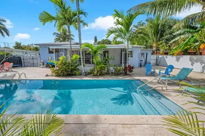 a swimming pool in front of a house with palm trees at The Blue Heaven Private Pool Hideaway Sleeps 11 in Golden Glades