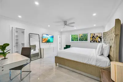a white bedroom with a bed and a desk and a window at Casa Sol in Richmond Heights