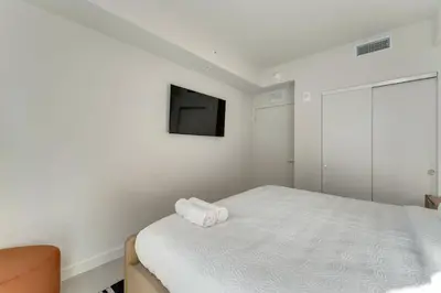 a white bedroom with a bed and a flat screen tv at Crosby Miami WTC 2BR 2BA High Floor Corner #3101 in Miami
