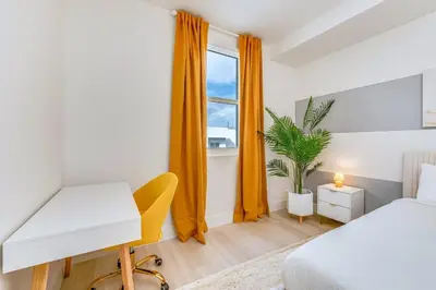 a bedroom with a desk and a bed and a window at Coastal 2BR-2BA Oasis Beach Pool Parking EV Estation in Hallandale Beach