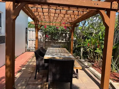 a wooden table and chairs under a wooden pergola at Coconut Villa in Hollywood
