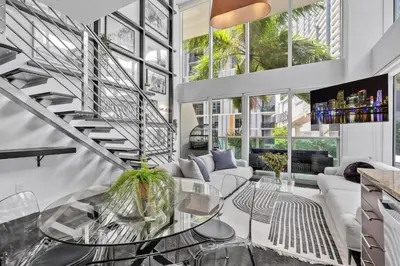 a living room with a staircase and a glass table at Urban Oasis 2BR Loft Residence in Brickell in Miami