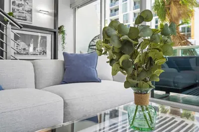 a vase with a plant on a glass table in a living room at Urban Oasis 2BR Loft Residence in Brickell in Miami