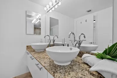 a white bathroom with two sinks and two mirrors at Urban Oasis 2BR Loft Residence in Brickell in Miami