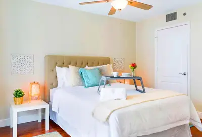 a bedroom with a white bed with a table on it at Poolside Brickell Gem Stay in Miami