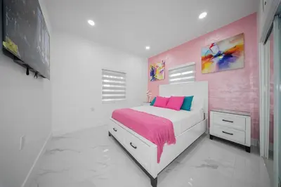 a bedroom with a white bed and a pink wall at Villa Shallat in Miami