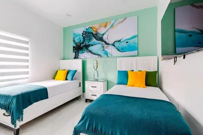 two beds in a bedroom with blue and yellow at Villa Shallat in Miami
