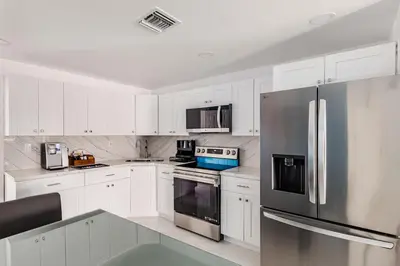 a kitchen with white cabinets and a stainless steel refrigerator at Villa Shallat in Miami