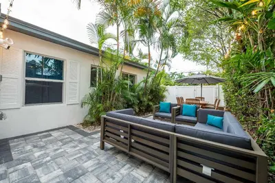 a patio with a couch and chairs and an umbrella at Walkable 1BR Apt near Las Olas - Fast WiFi & AC in Fort Lauderdale