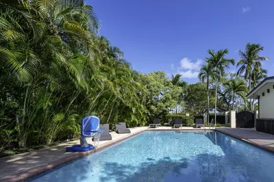 a swimming pool with chairs and palm trees at Aventura Lakefront in Miami