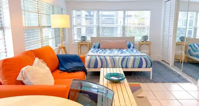 a living room with an orange couch and a bed at Lazy Cabana- Pool Canal Wilton Drive in Fort Lauderdale