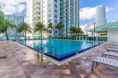 a large swimming pool with palm trees and buildings at Luxury 2BD Corner Loft with Stunning Miami River View in Miami