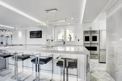 a white kitchen with a large island with bar stools at Versace Mansion Neighbor (Floors 2 & 3) Sleeps 12 in Miami Beach