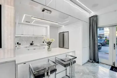 a white kitchen with a vase of flowers on a counter at Versace Mansion Neighbor (Floor 1) Sleeps 9 in Miami Beach