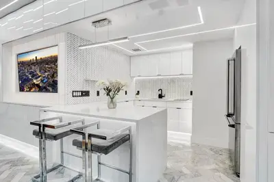 a white kitchen with a counter with stools at Versace Mansion Neighbor (Floor 1,2,3) Sleeps 21 in Miami Beach