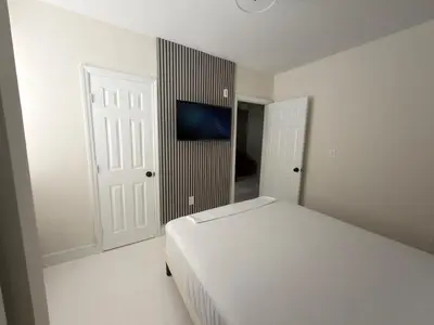 a white bedroom with a bed and a television at MB Playa Hotel & Apartments in Miami Beach