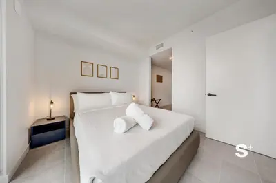 a white bedroom with a large bed with white pillows at Downtown Miami Cozy 1BR with Views in Miami