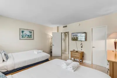 a bedroom with two beds and a desk with a mirror at Oceanfront Condo with Direct Beach Access in Hollywood Beach