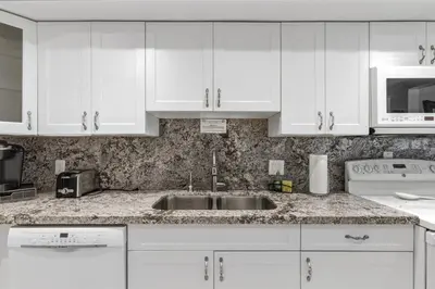 a kitchen with white cabinets and a sink at Oceanfront Condo with Direct Beach Access in Hollywood Beach