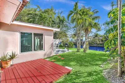 a house with a red wooden deck next to a yard at Waterfront ocean House Hollywood Hard Rock airport in Fort Lauderdale
