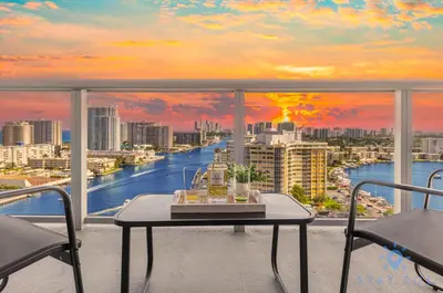 a balcony with a table and a view of a river at Beachwalk Condo in Hallandale Beach