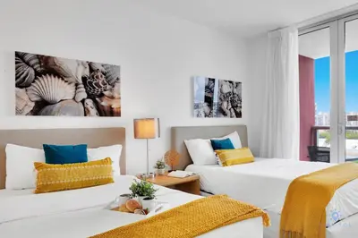 a hotel room with two beds and a window at Beachwalk Condo in Hallandale Beach