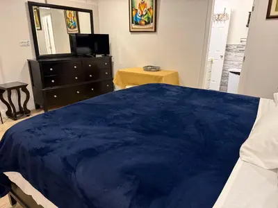 a bedroom with a blue bed with a dresser and a mirror at My Help Comes from The Lord Miami in Palmetto Bay