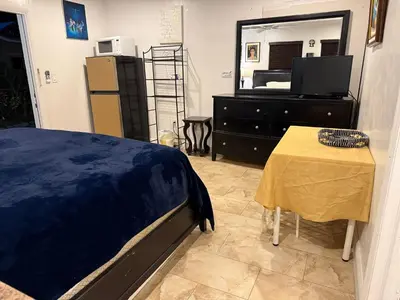 a bedroom with a bed and a table and a mirror at My Help Comes from The Lord Miami in Palmetto Bay