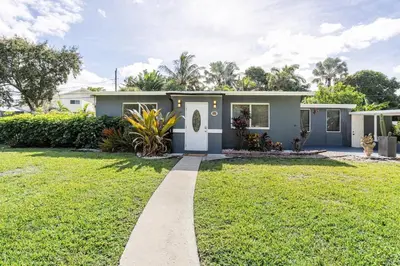 a house with a green lawn in front of it at Tropical Retreat- Heated Pool 3 Miles to the Beach in Fort Lauderdale