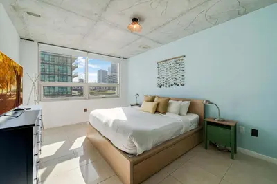 a bedroom with a large bed and a window at Midtown Rouge- Condo with City Views Pool & Gym in Miami
