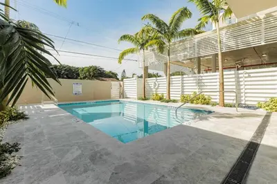 a swimming pool in front of a building with palm trees at Tropical Nest Residence in Hollywood
