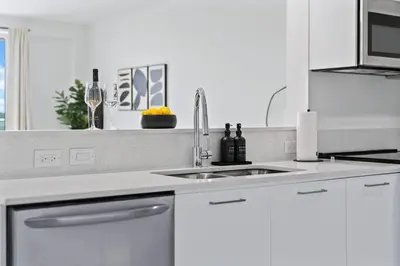 a white kitchen with a sink and a window at Pool & Gym | King Bed | Downtown Hollywood in Hollywood