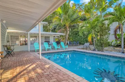 a swimming pool with blue chairs and palm trees at Take It Easy - Studio Pool Waterfront in Fort Lauderdale