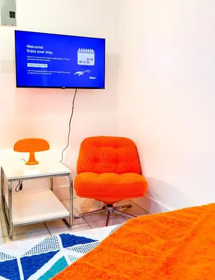 an orange chair sitting in a room with a tv at Take It Easy - Studio Pool Waterfront in Fort Lauderdale