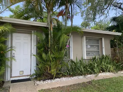 a house with a white door and a palm tree at Central Fort Lauderdale 2BR Cottage Near Beach in Fort Lauderdale