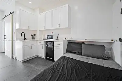 a kitchen with white cabinets and a black refrigerator at Studio in Design District in Miami