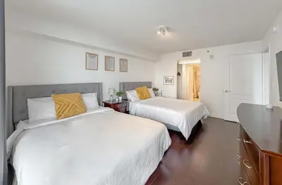 two beds in a bedroom with white walls and wood floors at Prime Brickell Stay with Pool Gym & Parking in Miami