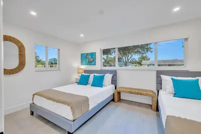 two beds in a room with two windows at Tropical Bliss 15 Min to Beach in Plantation