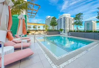 a swimming pool with two lounge chairs and an umbrella at MIA Worldcenter Premium 1BR Balcony & Rooftop Pool in Miami