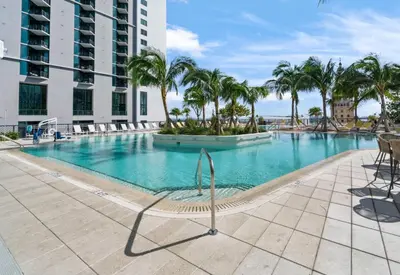 a swimming pool with palm trees and a building at Chic studio in Downtown with Gym and Pool in Miami