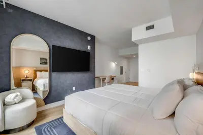 a bedroom with a large white bed and a mirror at Chic studio in Downtown with Gym and Pool in Miami