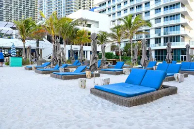 a sandy beach with blue lounge chairs and palm trees at Ocean Views Plus Beachside & Roofpool in Hollywood