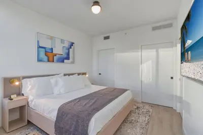 a white bedroom with a large bed and a glass wall at Miami Skyline 1BR Sleeps 4 with Elite Amenities in Miami
