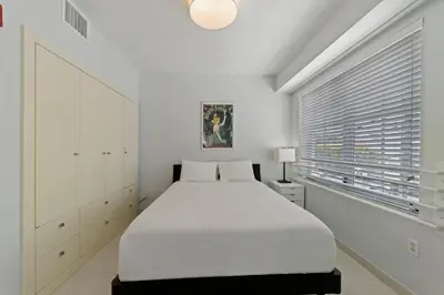 a white bedroom with a large bed and a window at South Beach, Perfect Oceanfront Apartment, Iconic Art Deco Building, Walk to Everything! in Miami Beach