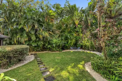 a garden with a bench and trees and grass at Spacious & Stylish 2BR Retreat near Victoria Park in Fort Lauderdale
